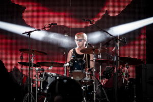 Schlagzeuger mit cooler Sonnenbrille und zwei Lichtspots von den Seiten