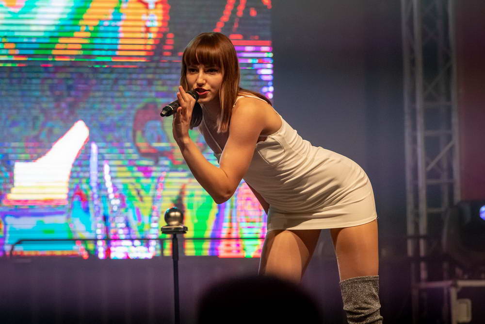 Sängerin im kurzen sexy Kleid als Kylie Minoque beugt sich zum Publikum.